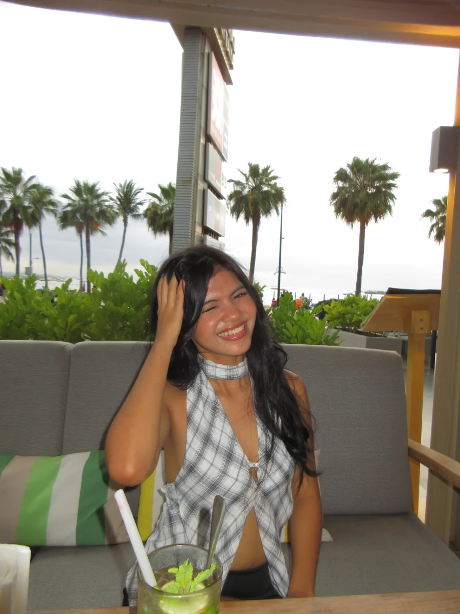 Cercie laughing on a balcony with palm trees behind her